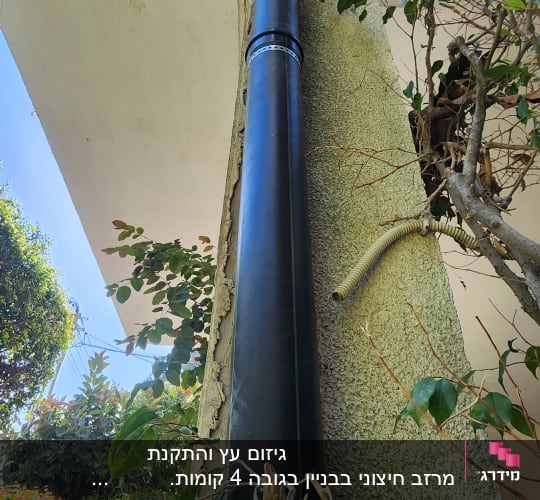 צינור ניקוז שחור מחובר לקיר בניין